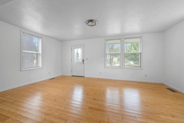 interior space with a textured ceiling and light hardwood / wood-style flooring