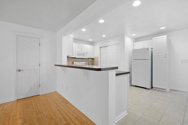 kitchen featuring kitchen peninsula, light hardwood / wood-style flooring, white cabinets, and white appliances