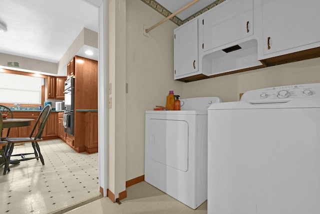 clothes washing area with cabinets and washer and dryer