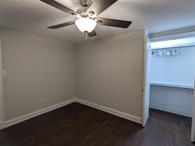 empty room with dark wood-type flooring, ceiling fan, and a textured ceiling