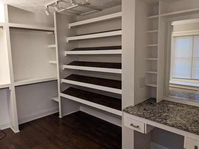 walk in closet featuring dark wood-type flooring and built in desk