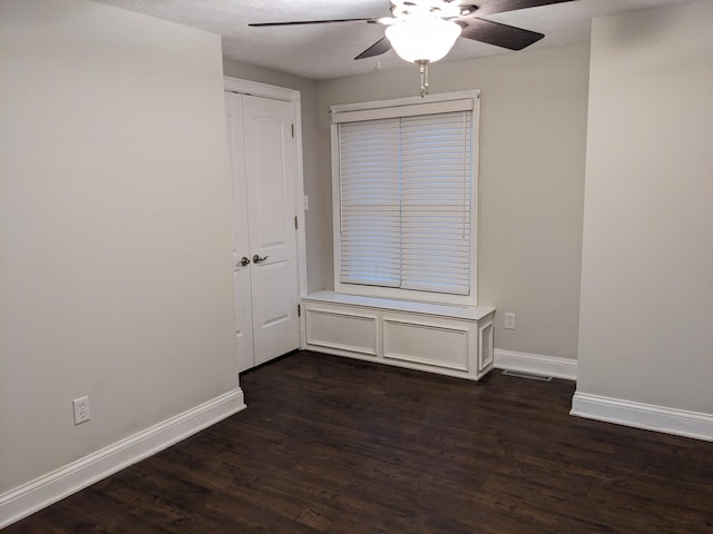 unfurnished room featuring dark wood-type flooring and ceiling fan