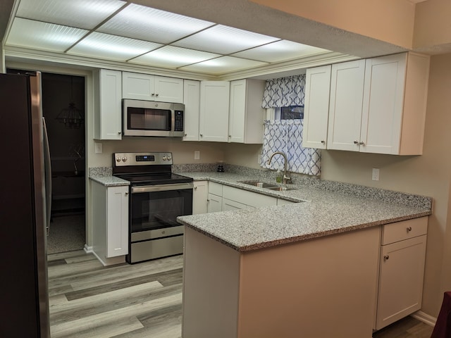 kitchen with sink, stainless steel appliances, kitchen peninsula, and white cabinets