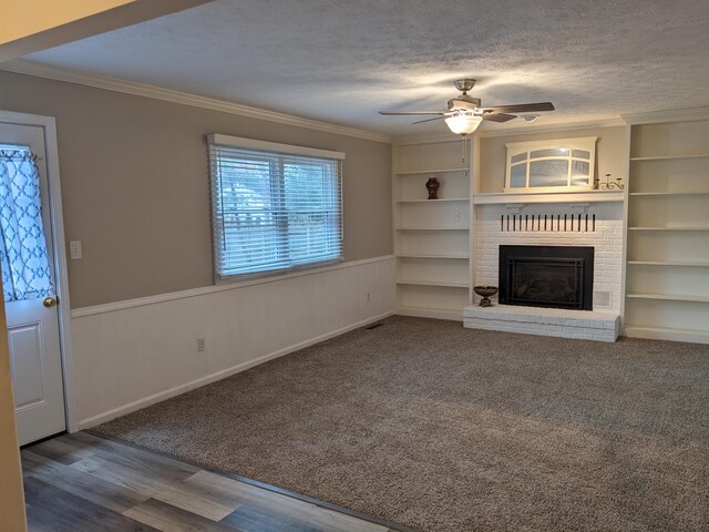 unfurnished living room with ornamental molding, a brick fireplace, wood-type flooring, and a textured ceiling