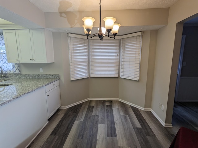 unfurnished dining area with dark hardwood / wood-style floors, a chandelier, sink, and a textured ceiling