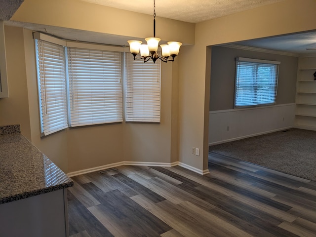 unfurnished dining area with dark hardwood / wood-style flooring, a textured ceiling, and a chandelier