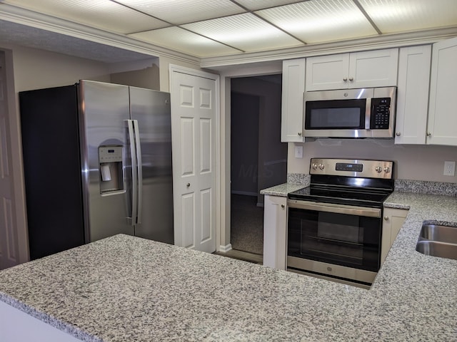 kitchen with white cabinetry, stainless steel appliances, light stone countertops, and kitchen peninsula