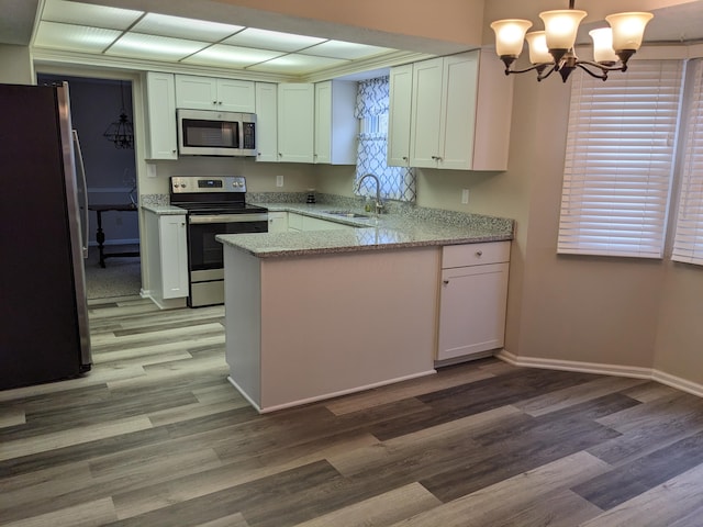 kitchen featuring sink, light stone counters, decorative light fixtures, appliances with stainless steel finishes, and white cabinets