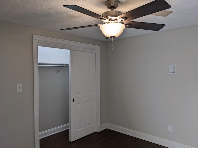 unfurnished bedroom with dark wood-type flooring, a closet, ceiling fan, and a textured ceiling