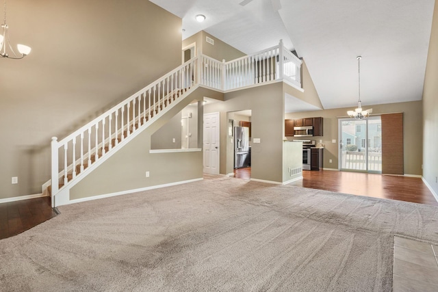 unfurnished living room featuring wood-type flooring, high vaulted ceiling, and an inviting chandelier