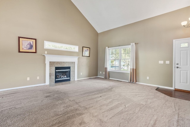 unfurnished living room with carpet flooring, high vaulted ceiling, and a tiled fireplace