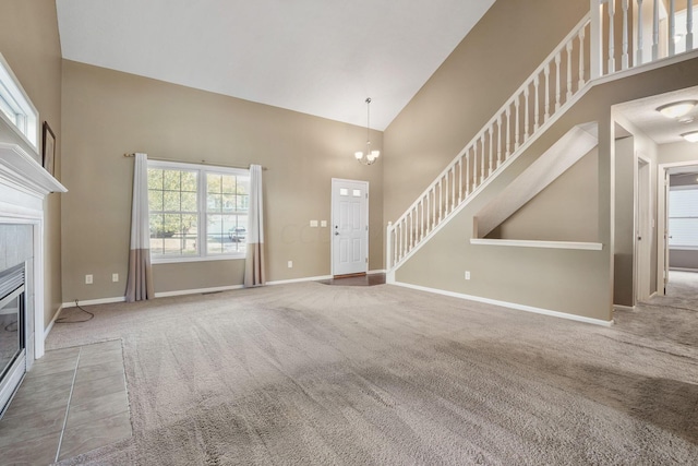 unfurnished living room with carpet flooring, a tile fireplace, high vaulted ceiling, and a notable chandelier