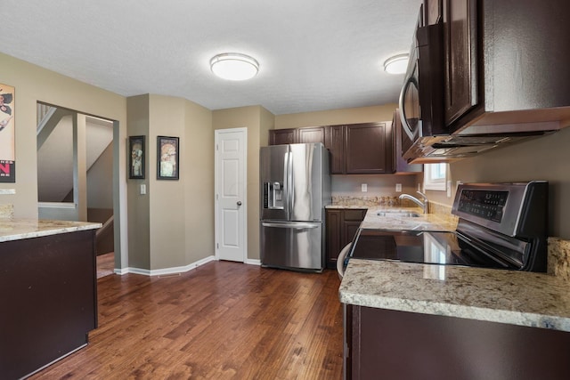 kitchen featuring dark hardwood / wood-style flooring, dark brown cabinetry, light stone counters, and appliances with stainless steel finishes