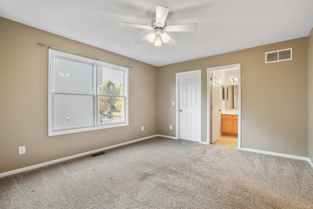 unfurnished bedroom featuring light carpet, ensuite bath, and ceiling fan