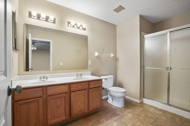 bathroom featuring ceiling fan, vanity, an enclosed shower, and a textured ceiling