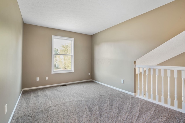 carpeted empty room with a textured ceiling