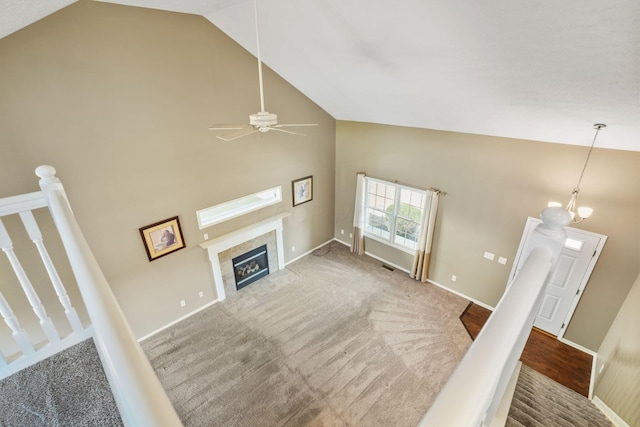 unfurnished living room featuring a fireplace, carpet, ceiling fan with notable chandelier, and high vaulted ceiling