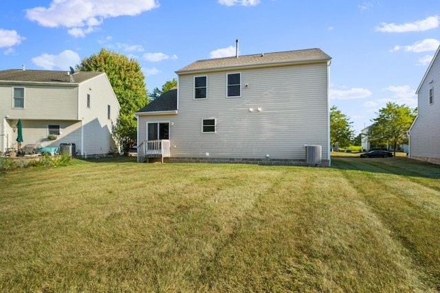 back of property with central air condition unit and a lawn