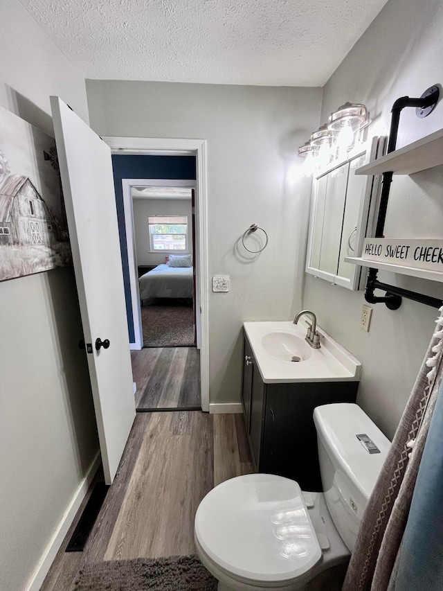 bathroom with hardwood / wood-style floors, a textured ceiling, and toilet