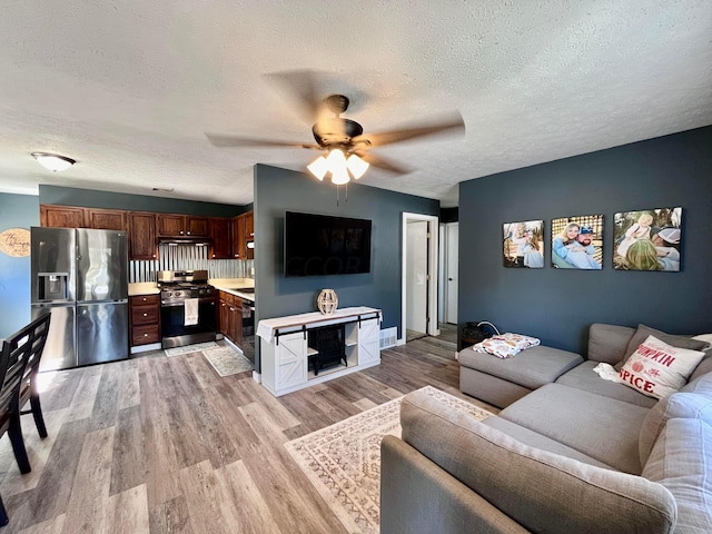 living room featuring a textured ceiling, light hardwood / wood-style flooring, and ceiling fan