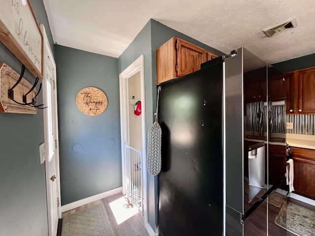 kitchen featuring black fridge, dark wood-type flooring, and a textured ceiling