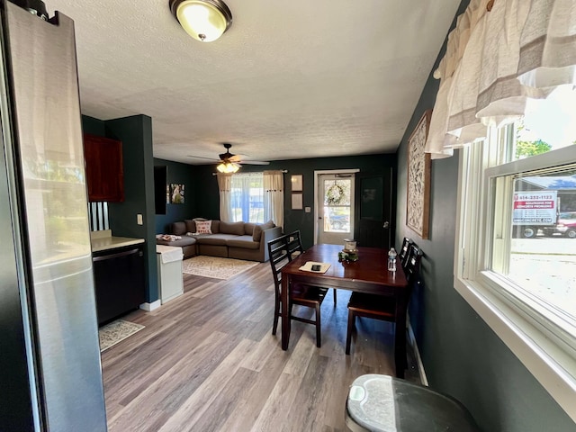 dining room with ceiling fan, a textured ceiling, and light wood-type flooring