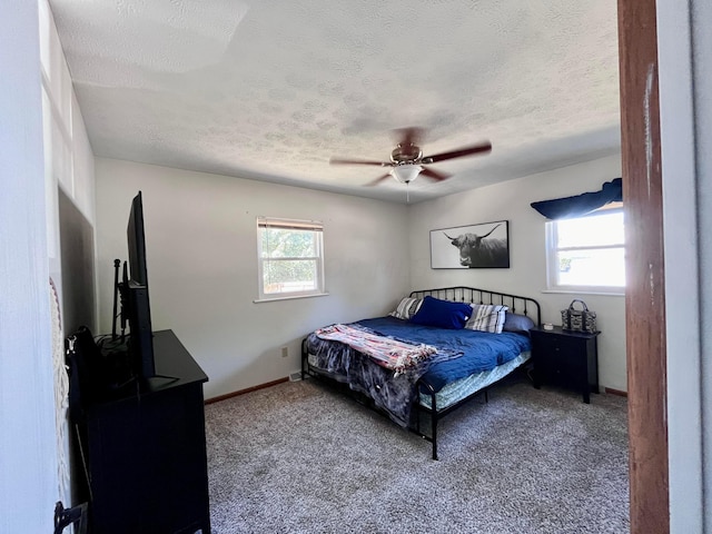 carpeted bedroom with ceiling fan, a textured ceiling, and multiple windows