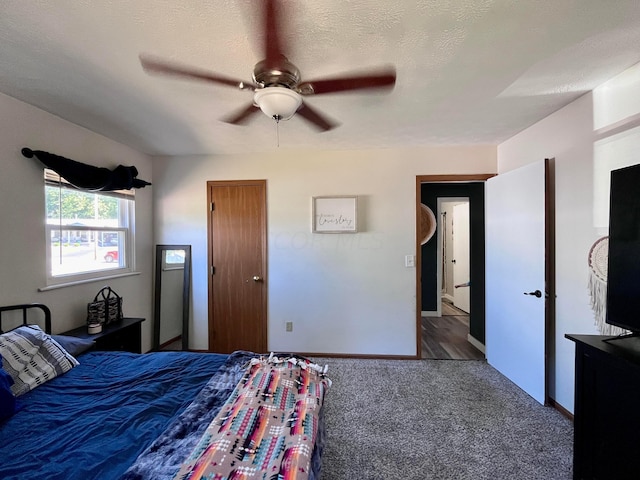 bedroom with ceiling fan, a textured ceiling, and dark colored carpet