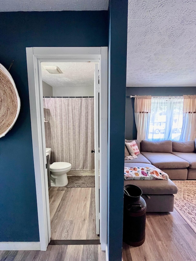 interior space featuring wood-type flooring, a textured ceiling, and toilet