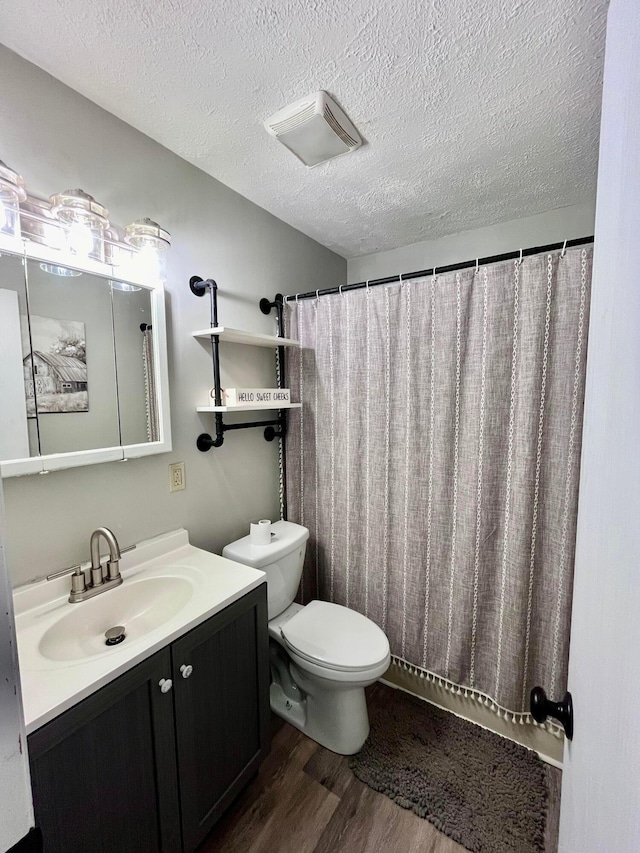 bathroom featuring vanity, wood-type flooring, a textured ceiling, and toilet