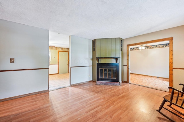 5010 Chipman Dr, Columbus, OH 43232 - unfurnished living room with light wood-type flooring, a textured ceiling, a large fireplace, and baseboards