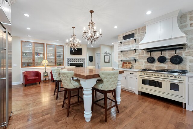 kitchen featuring a fireplace, wood counters, backsplash, premium appliances, and custom exhaust hood