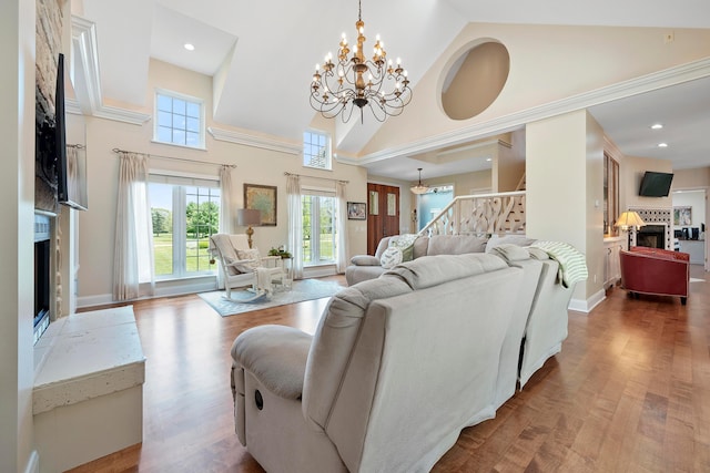 living area with high vaulted ceiling, a notable chandelier, a healthy amount of sunlight, and a fireplace