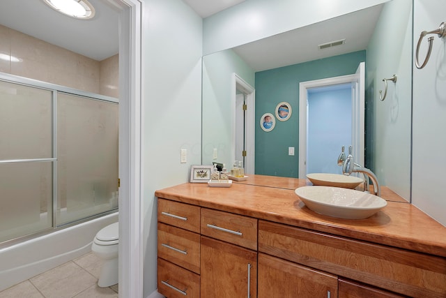 full bath featuring visible vents, vanity, shower / bath combination with glass door, toilet, and tile patterned floors