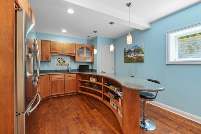kitchen with a breakfast bar area, stainless steel fridge, dark wood-type flooring, brown cabinets, and a sink