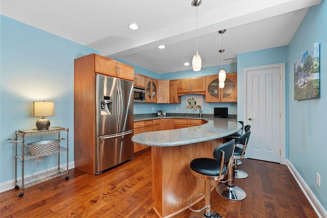 kitchen with brown cabinets, appliances with stainless steel finishes, a sink, baseboards, and glass insert cabinets