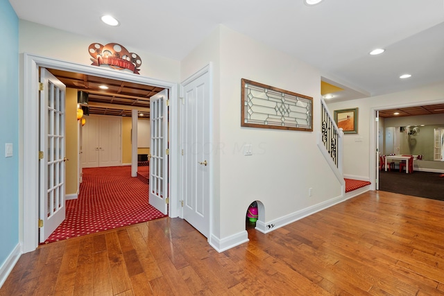 corridor with hardwood / wood-style floors, baseboards, stairway, recessed lighting, and french doors