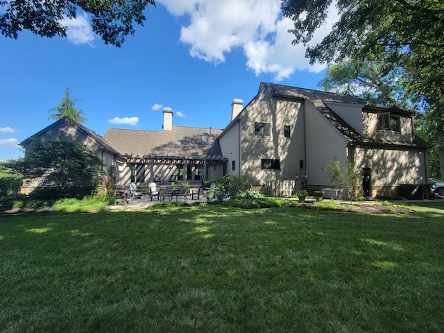 rear view of property featuring a chimney, a patio area, a yard, a pergola, and stucco siding