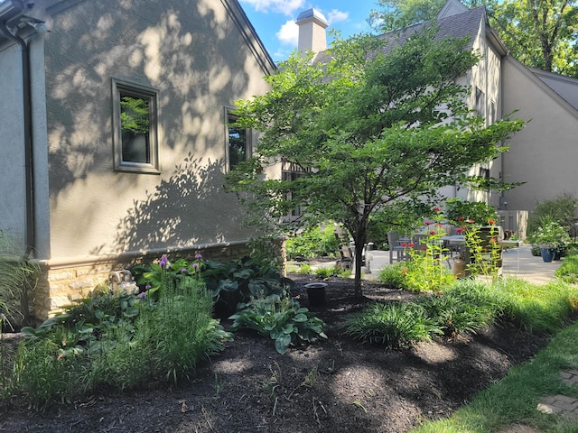 view of side of property featuring a chimney, stone siding, and stucco siding