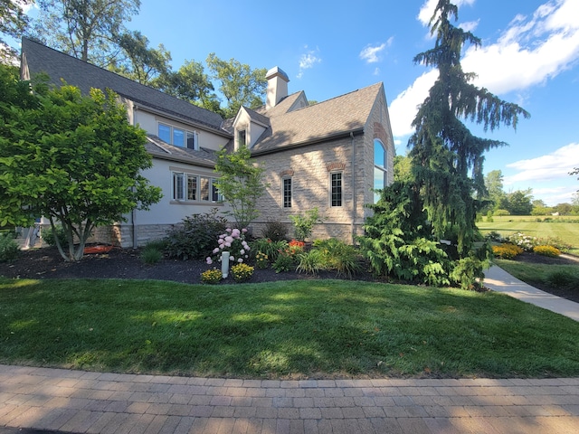 view of side of property featuring a chimney, a yard, stucco siding, and stone siding