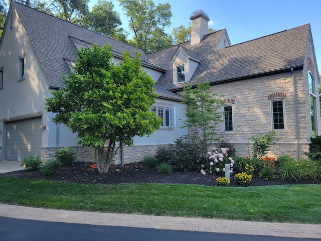 view of side of property featuring a chimney, a shingled roof, stone siding, and stucco siding