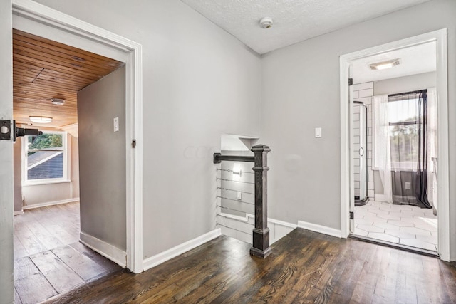 corridor with dark hardwood / wood-style flooring and a textured ceiling