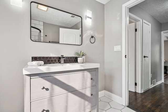 bathroom with hardwood / wood-style flooring, vanity, and a textured ceiling