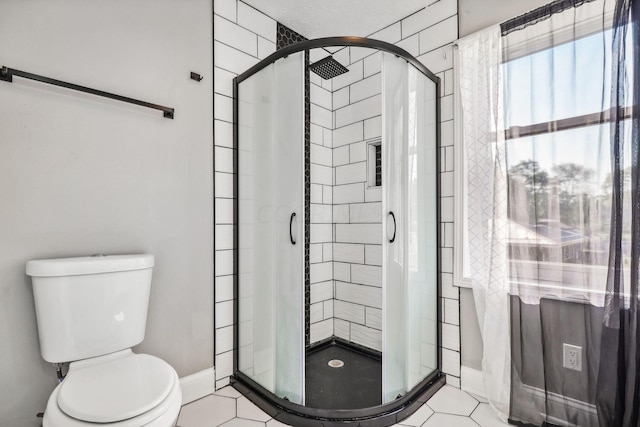 bathroom with tile patterned floors, toilet, and a shower with door