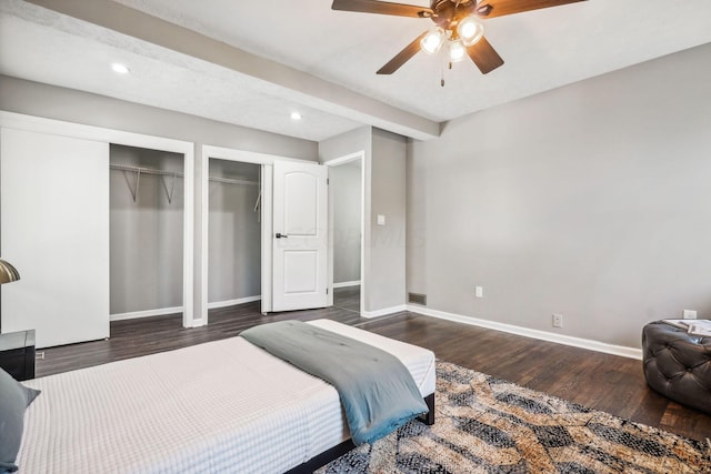 bedroom with two closets, ceiling fan, and dark hardwood / wood-style floors