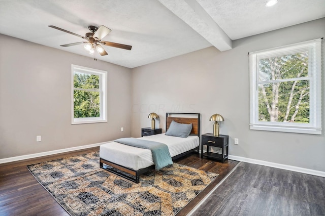 bedroom with ceiling fan, dark hardwood / wood-style floors, a textured ceiling, and multiple windows