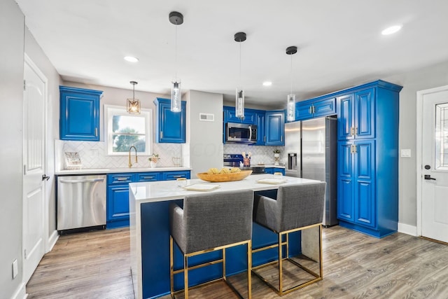 kitchen with a center island, stainless steel appliances, light wood-type flooring, and blue cabinets