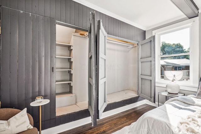 bedroom with dark hardwood / wood-style floors, a closet, crown molding, and wood walls