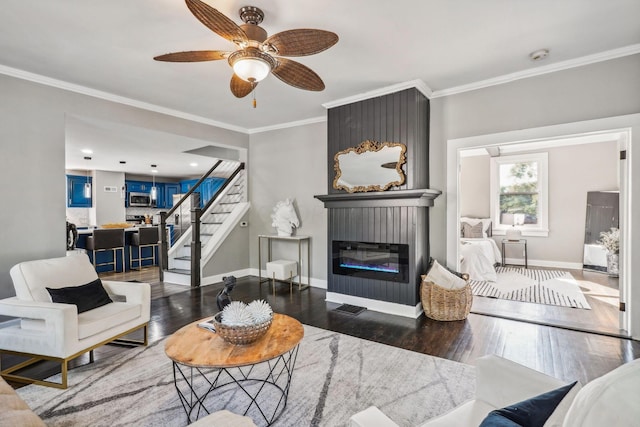 living room featuring a fireplace, ceiling fan, ornamental molding, and dark wood-type flooring