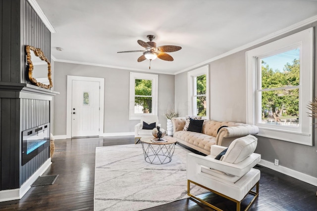 living room with dark hardwood / wood-style flooring, ornamental molding, and a wealth of natural light